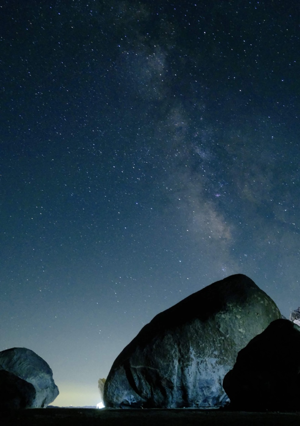 A starry night sky above dark rocks